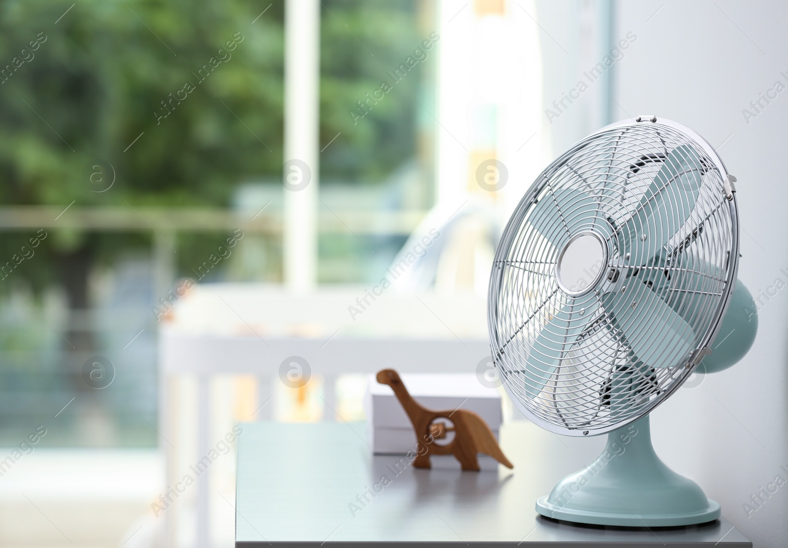 Photo of Modern fan on commode in baby room. Space for text