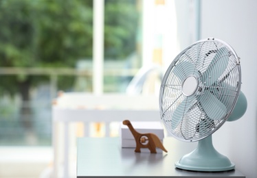 Photo of Modern fan on commode in baby room. Space for text