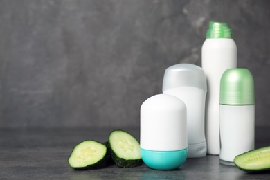 Photo of Different deodorants and cucumber on table. Personal hygiene
