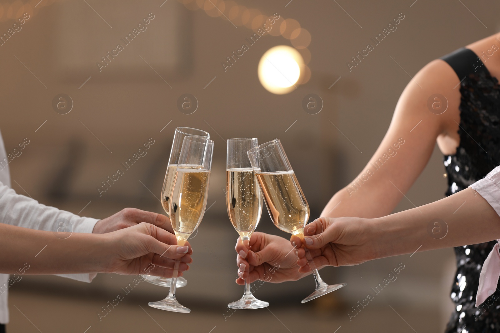 Photo of People clinking glasses of champagne against blurred background, closeup. Bokeh effect