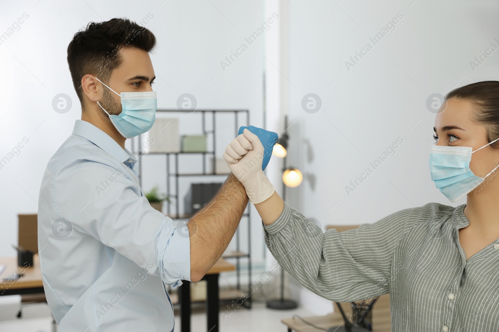 Photo of People greeting each other by bumping fists instead of handshake in office