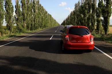 Photo of Red car on asphalt road in countryside