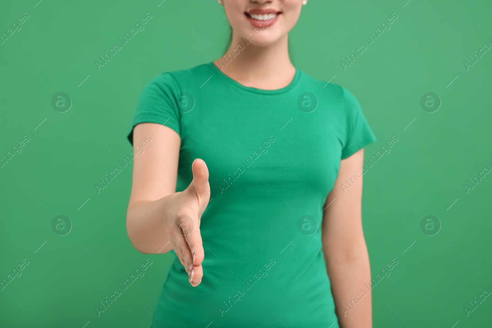 Photo of Woman welcoming and offering handshake on green background, closeup