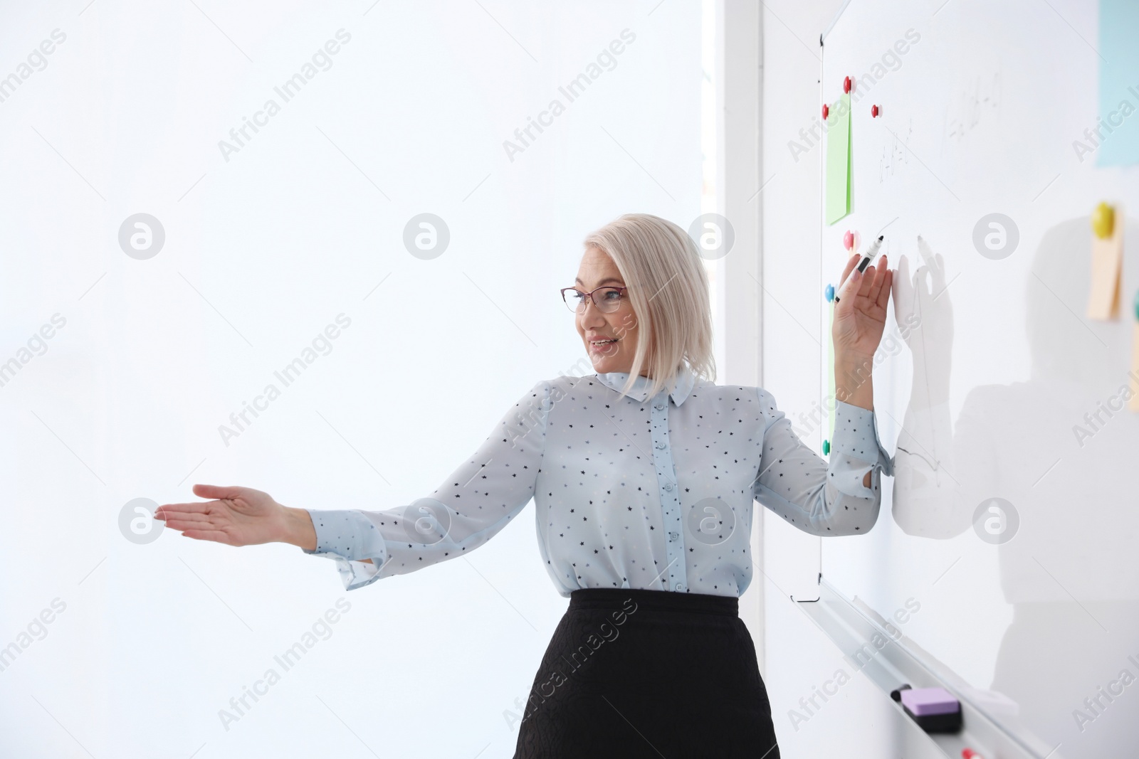 Photo of Mature teacher near whiteboard in modern classroom