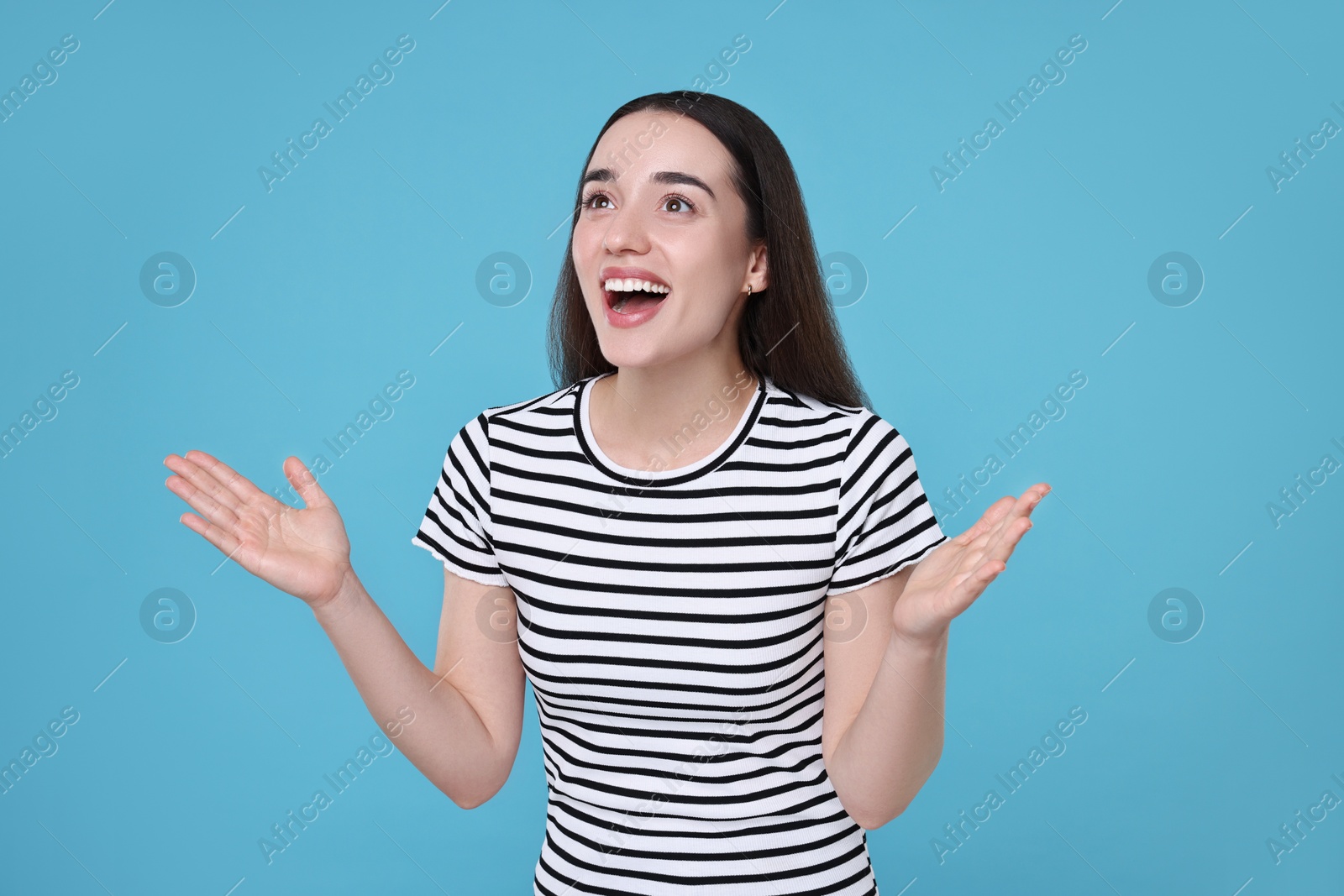 Photo of Portrait of happy surprised woman on light blue background