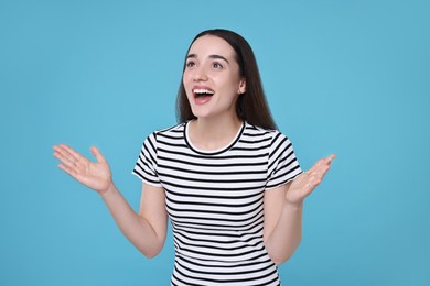 Portrait of happy surprised woman on light blue background