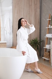 Photo of Beautiful young woman sitting on edge of tub in bathroom