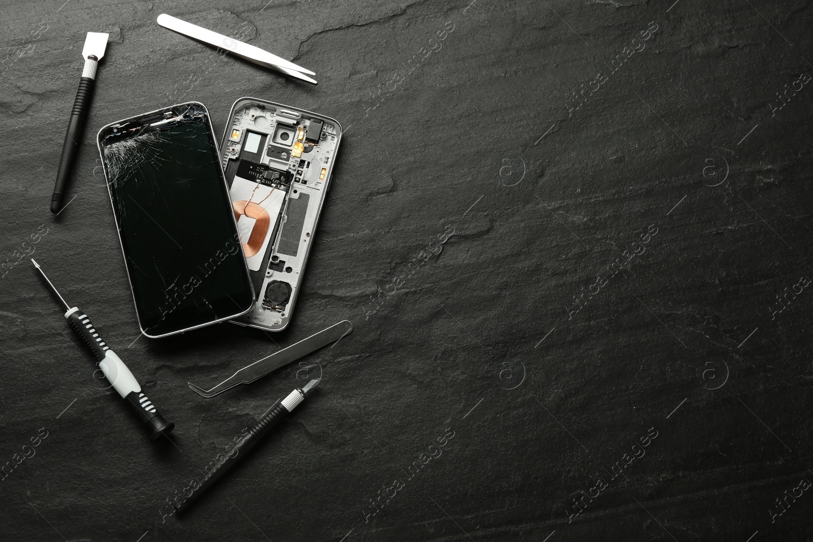 Photo of Damaged smartphone and repair tools on black background, flat lay. Space for text