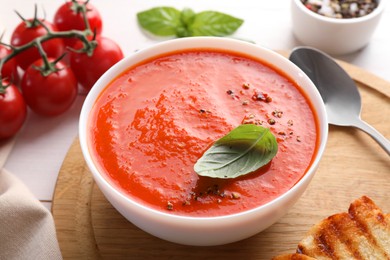 Photo of Delicious tomato soup served on white table, closeup