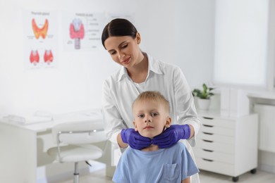 Endocrinologist examining boy's thyroid gland at hospital