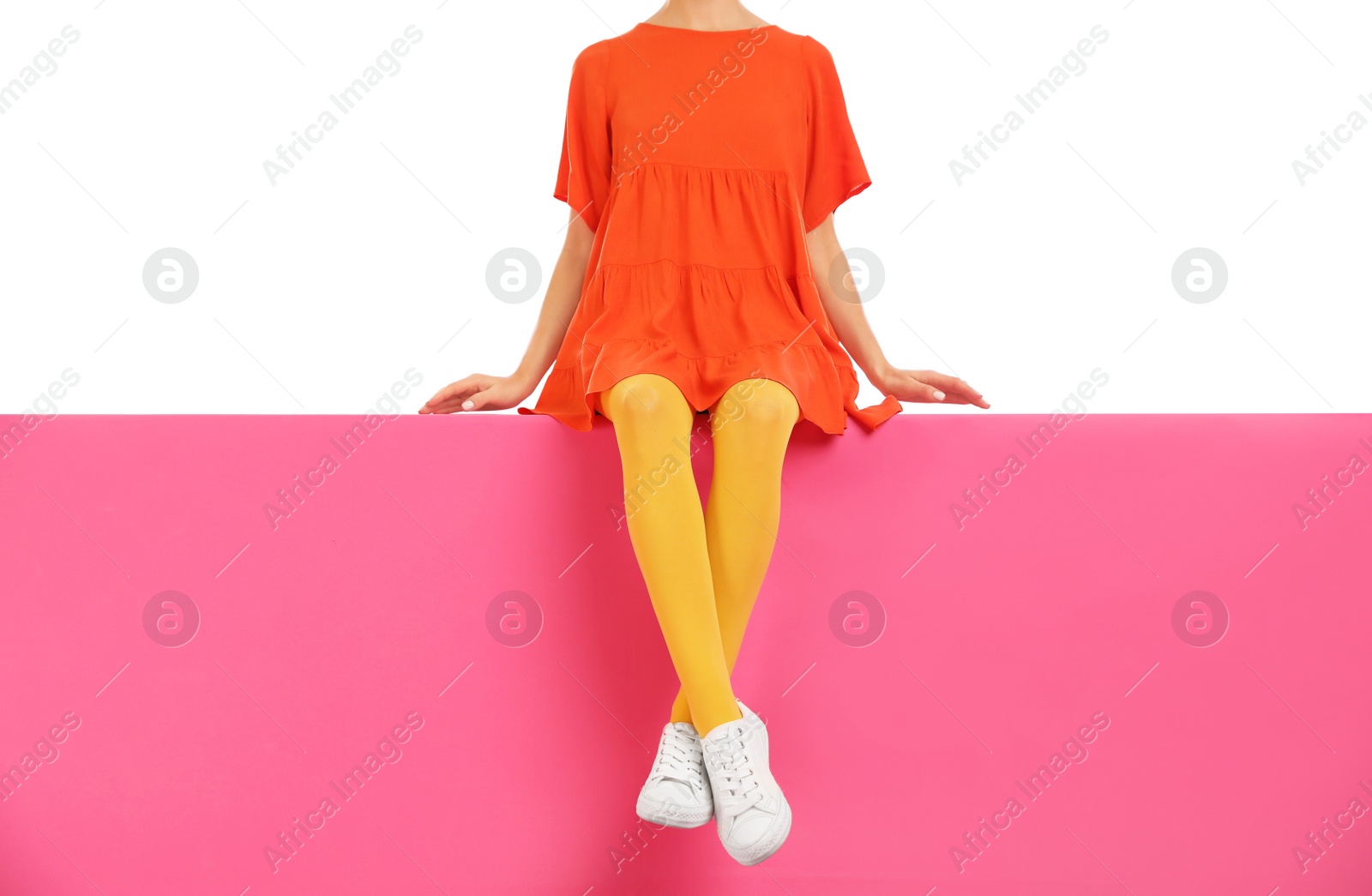 Photo of Woman wearing yellow tights and stylish shoes sitting on color background, closeup