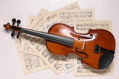 Photo of Violin and music sheets on white wooden table, top view