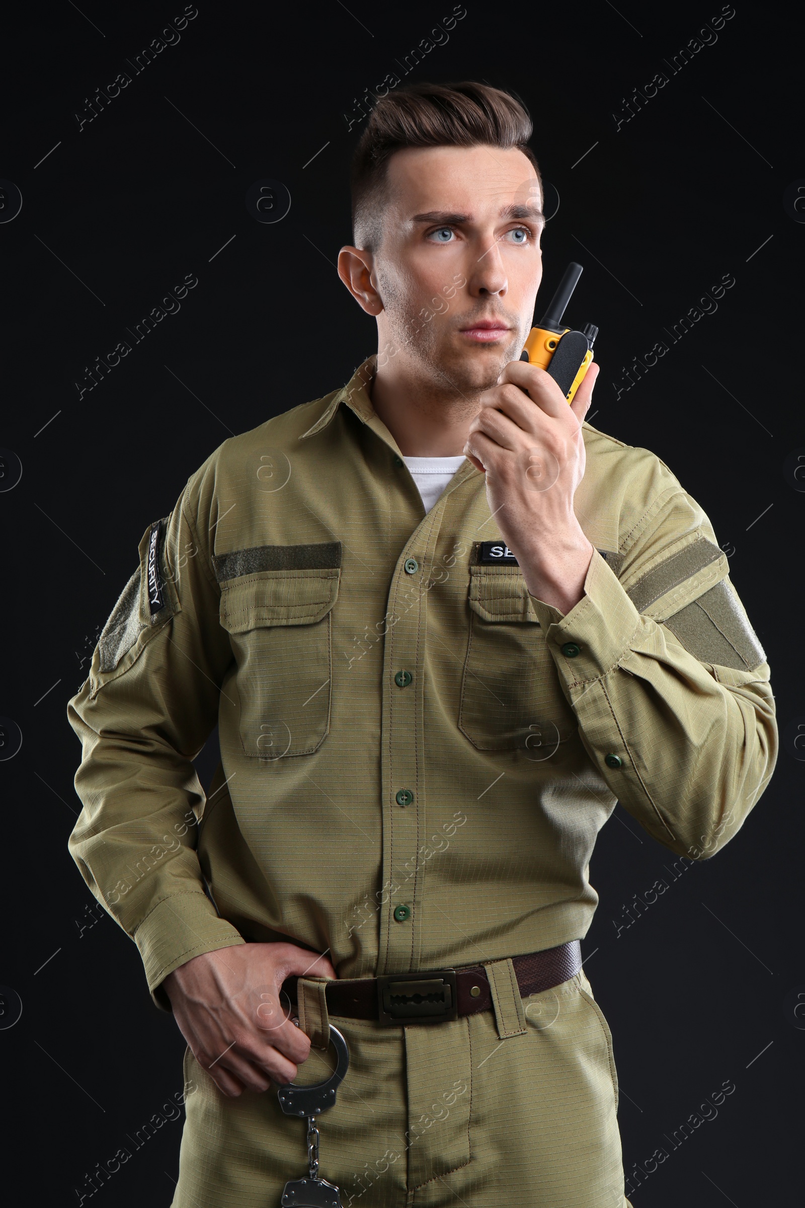 Photo of Male security guard using portable radio transmitter on dark background