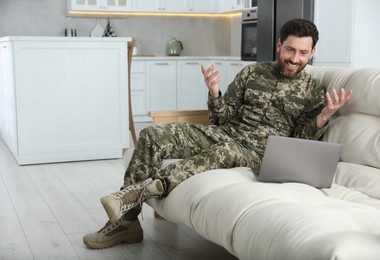 Photo of Happy soldier using video chat on laptop at home. Military service