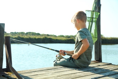 Little boy fishing alone on sunny day. Space for text