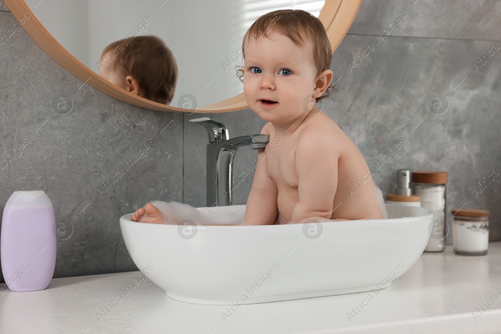 Photo of Cute little baby bathing in sink at home