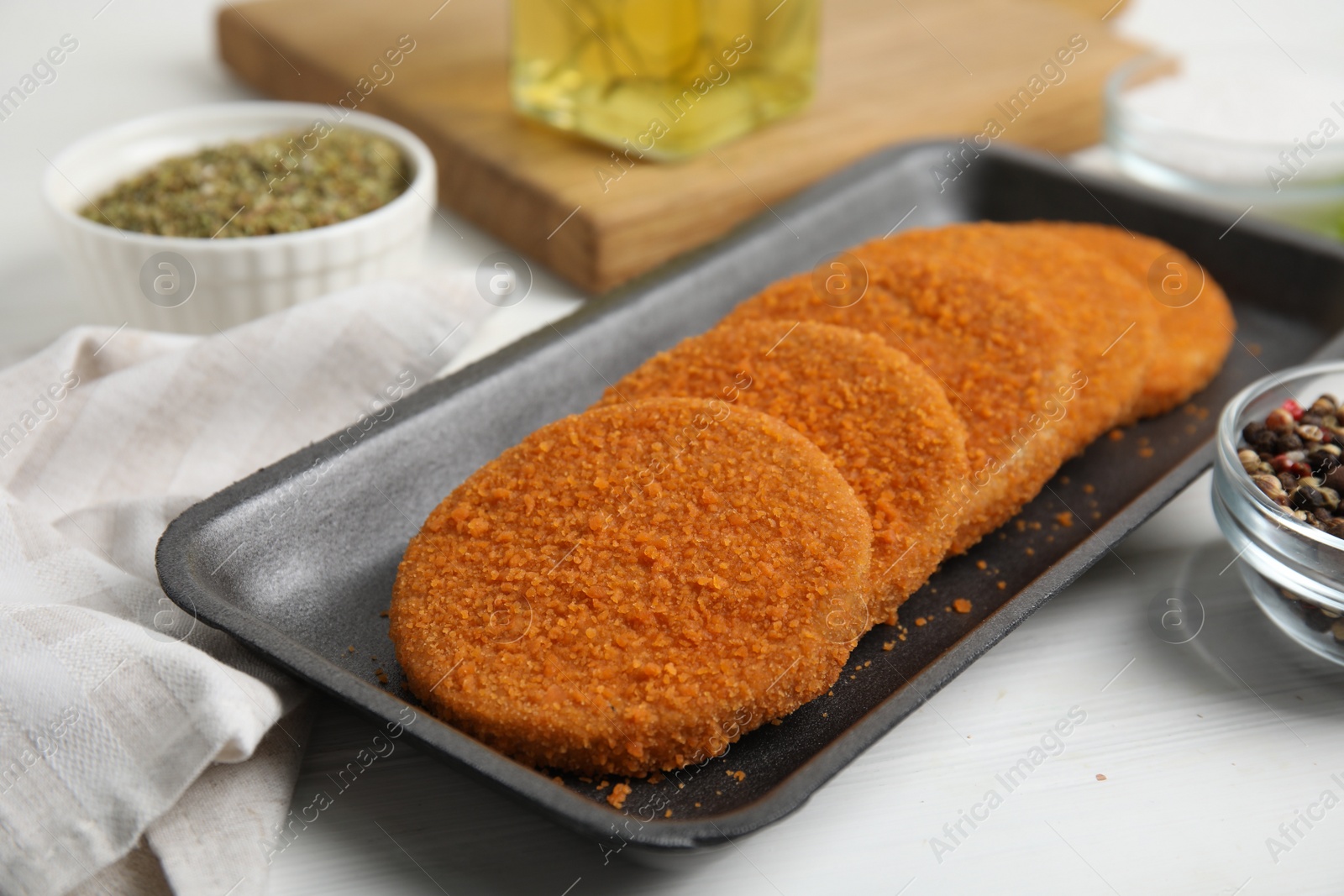 Photo of Uncooked breaded cutlets on white wooden table. Freshly frozen semi-finished product