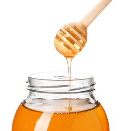 Honey dripping from dipper into jar on white background