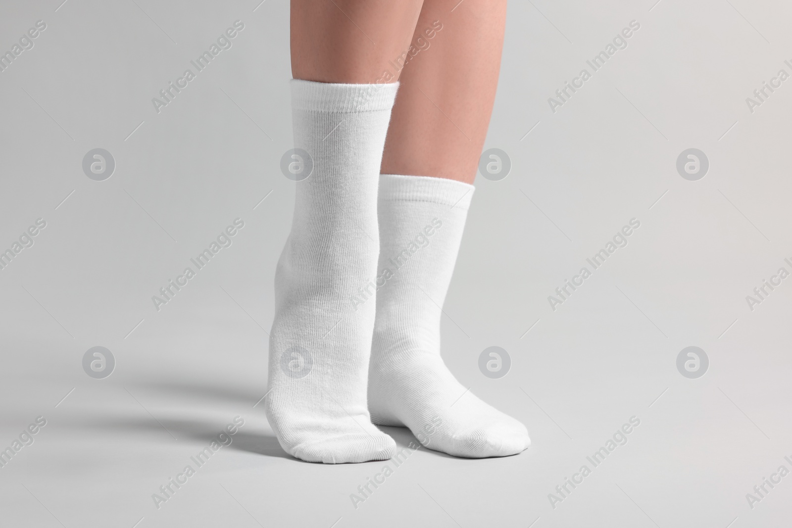 Photo of Woman in stylish white socks on light grey background, closeup