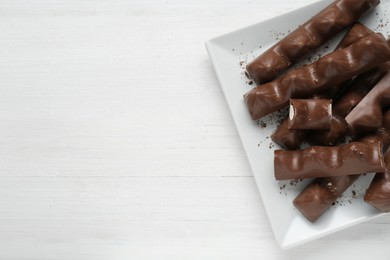 Photo of Tasty chocolate bars on white wooden table, top view. Space for text