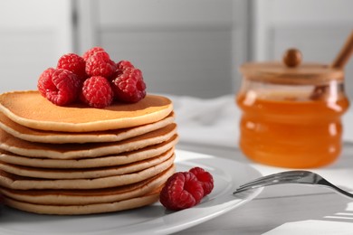 Photo of Stack of tasty pancakes with raspberries on white wooden table, closeup. Space for text