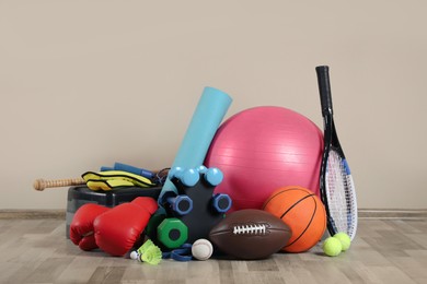 Photo of Set of different sports equipment on floor near beige wall