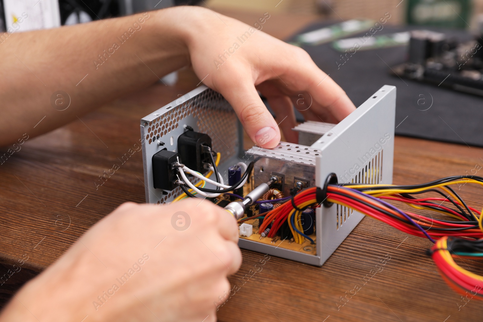 Photo of Male technician repairing power supply unit at table, closeup