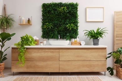 Green artificial plants, vanity and different personal care products in bathroom