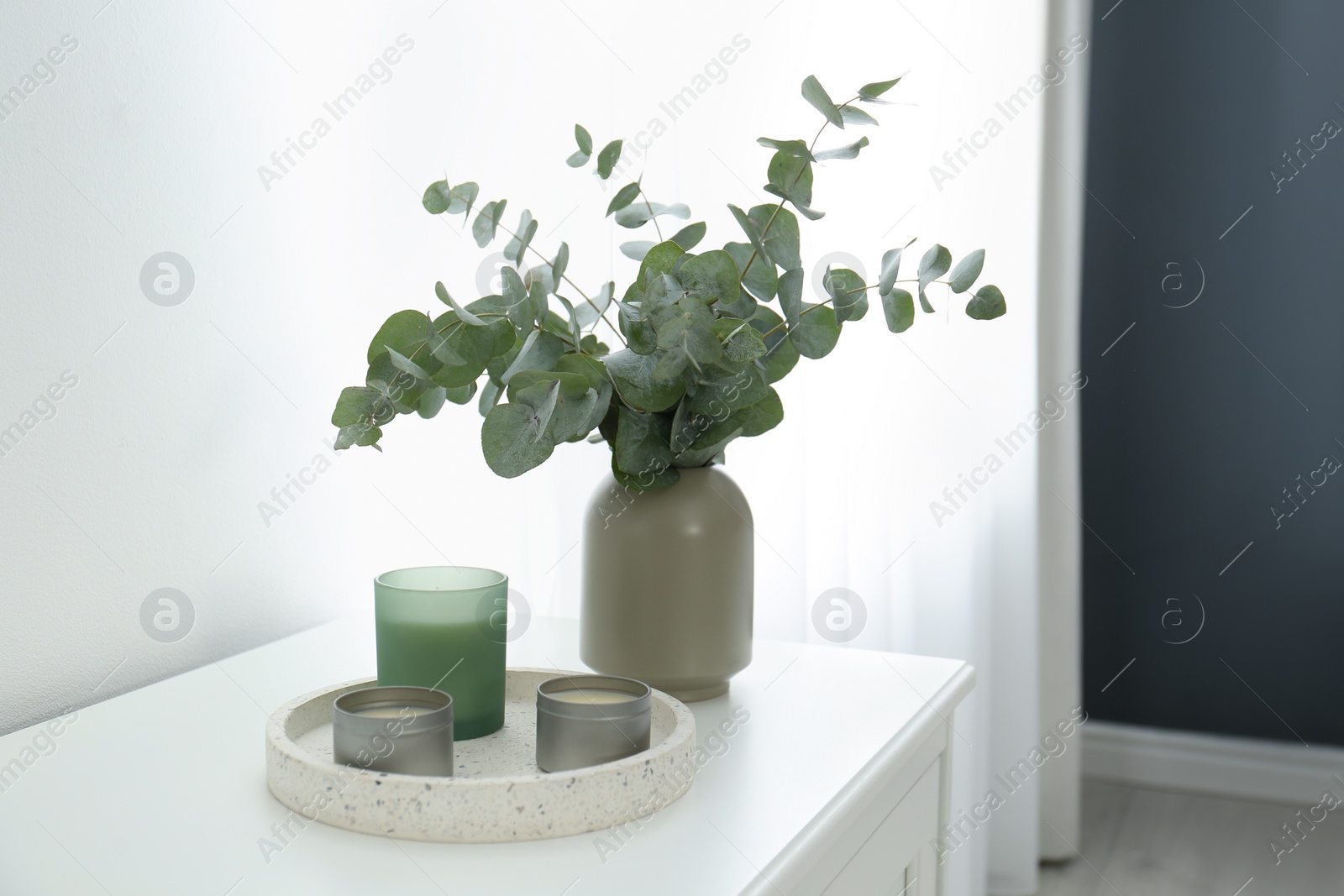 Photo of Candles and eucalyptus branches on white table indoors. Interior element