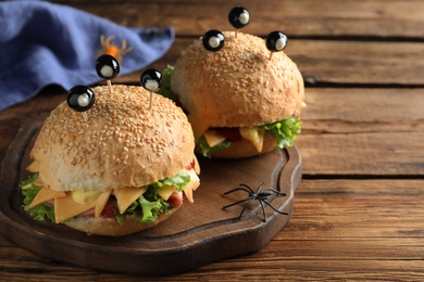 Photo of Cute monster burgers served on wooden table. Halloween party food