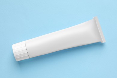 Photo of Tube of ointment on light blue background, top view. Space for text