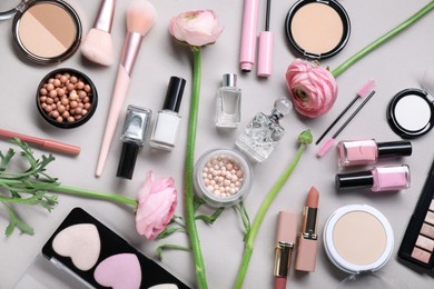 Flat lay composition with different makeup products and beautiful spring flowers on gray background