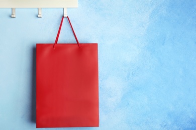 Photo of Rack with paper shopping bag on color wall. Mockup for design