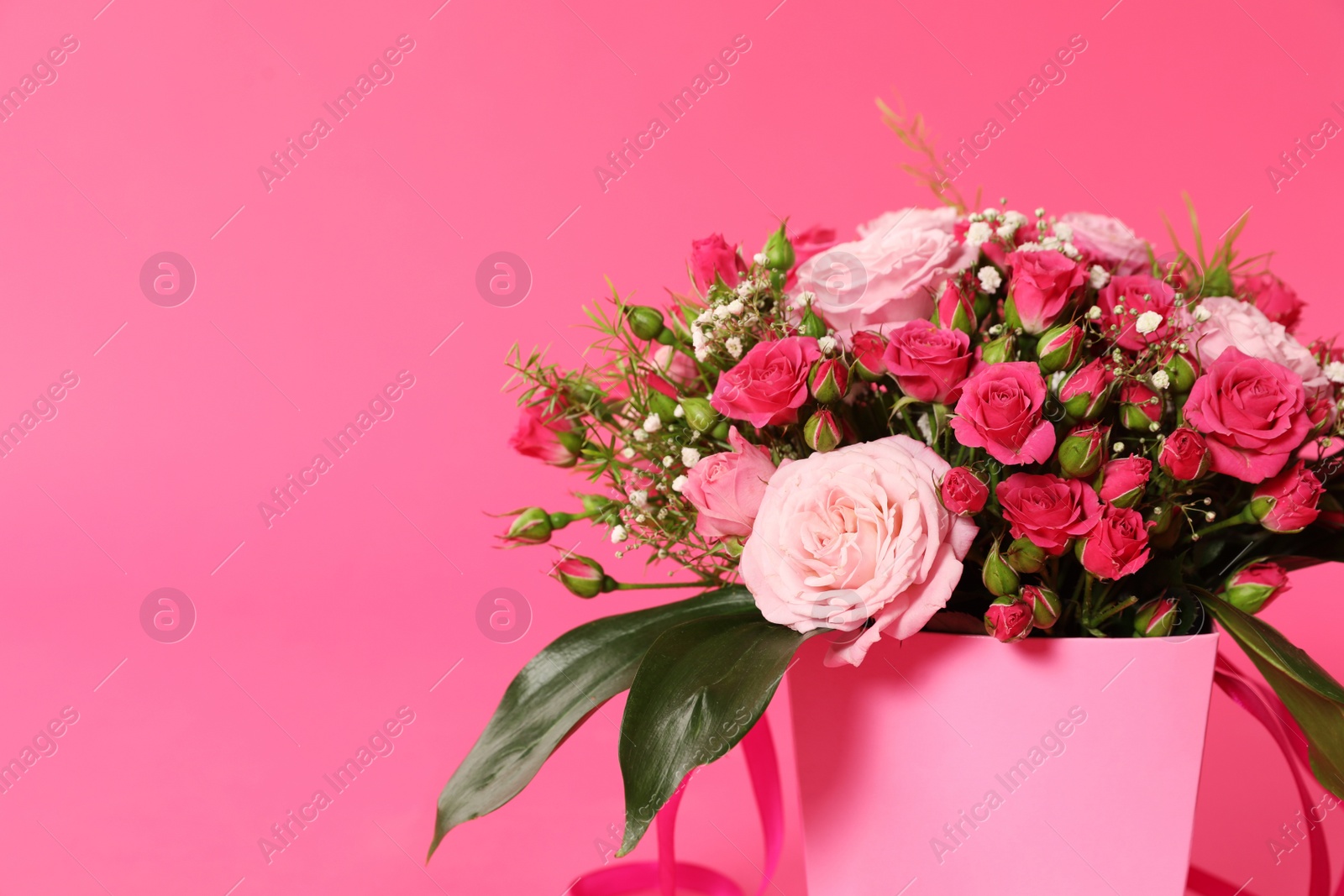 Photo of Beautiful bouquet of flowers in paper gift box on color background. Space for text