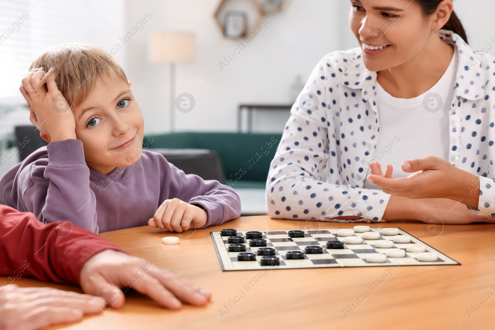 Photo of Family playing checkers at wooden table in room