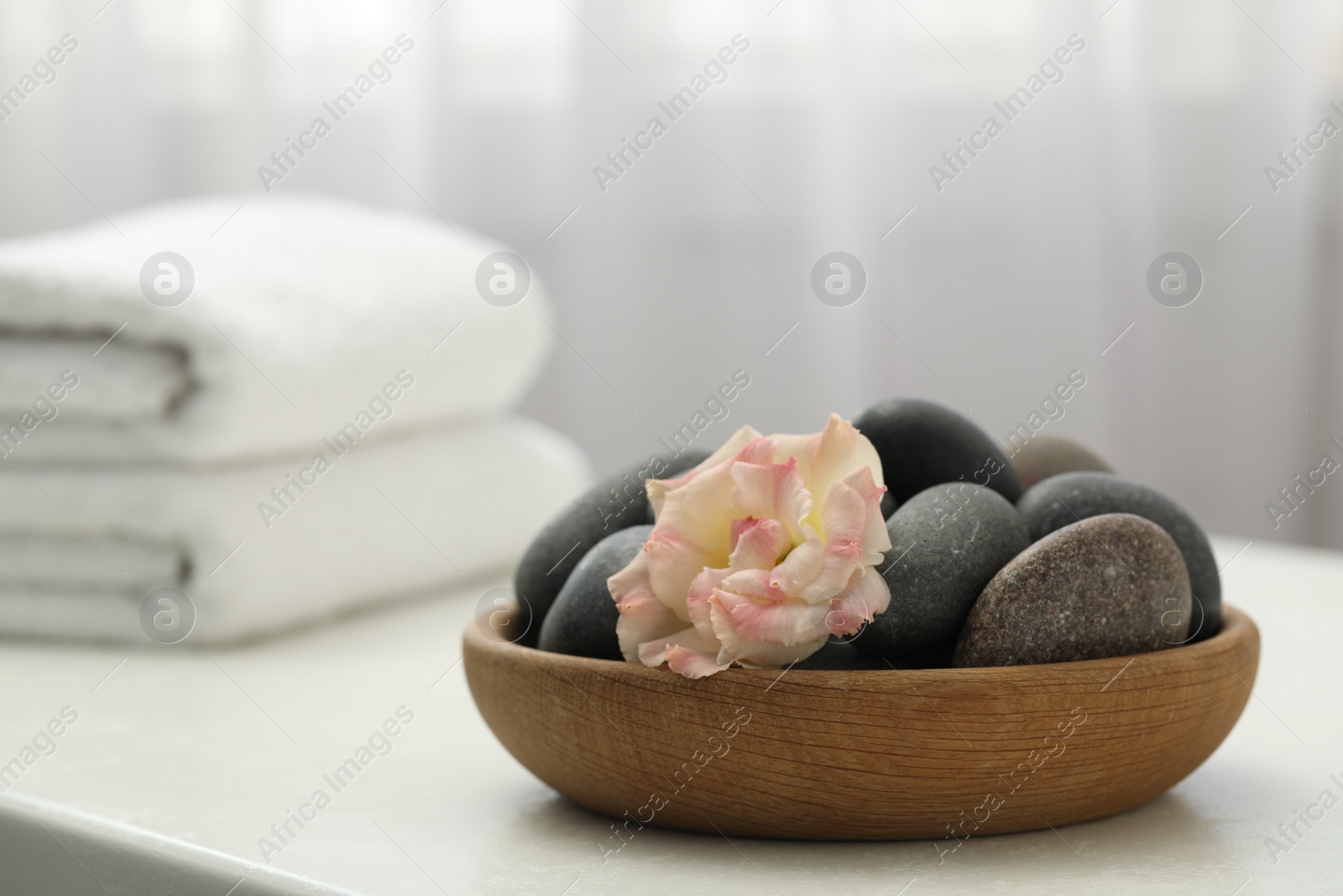 Photo of Spa stones and flowers on white table indoors