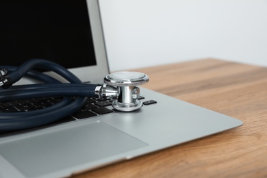 Laptop with stethoscope on table, closeup. Computer repair