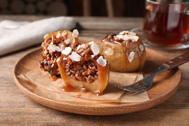Photo of Delicious baked apples with nuts and caramel served on wooden table
