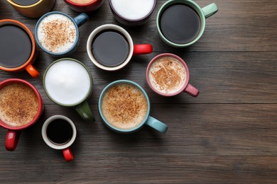 Photo of Many different cups with aromatic hot coffee on wooden table, flat lay