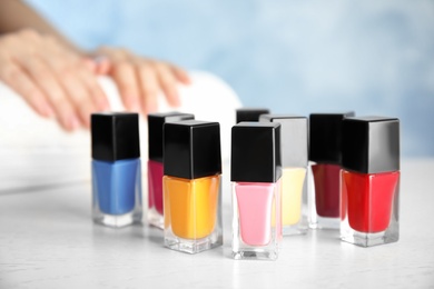Photo of Bottles of bright nail polish and blurred woman on background