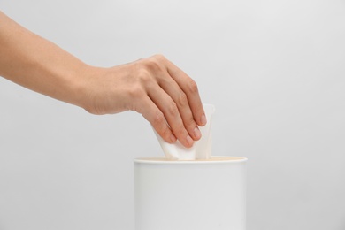 Photo of Woman taking paper tissue from holder on light background, closeup