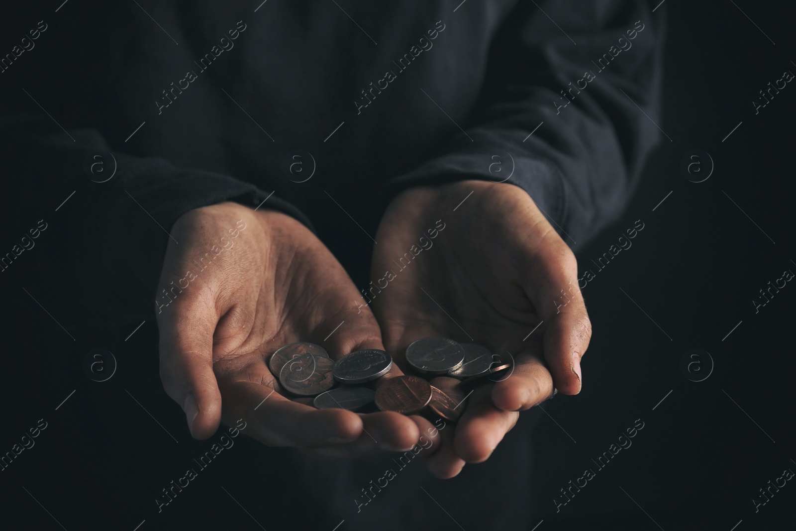 Photo of Poor woman holding coins on dark background, closeup