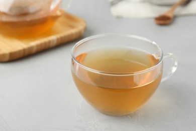 Photo of Glass cup of buckwheat tea on light grey table