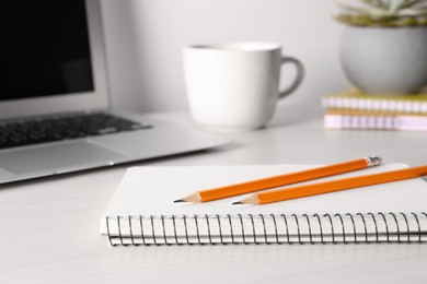 Notebook, pencils and laptop on white table