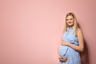 Photo of Beautiful pregnant woman in dress on color background. Space for text