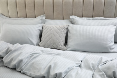 Many soft pillows and blanket on large comfortable bed