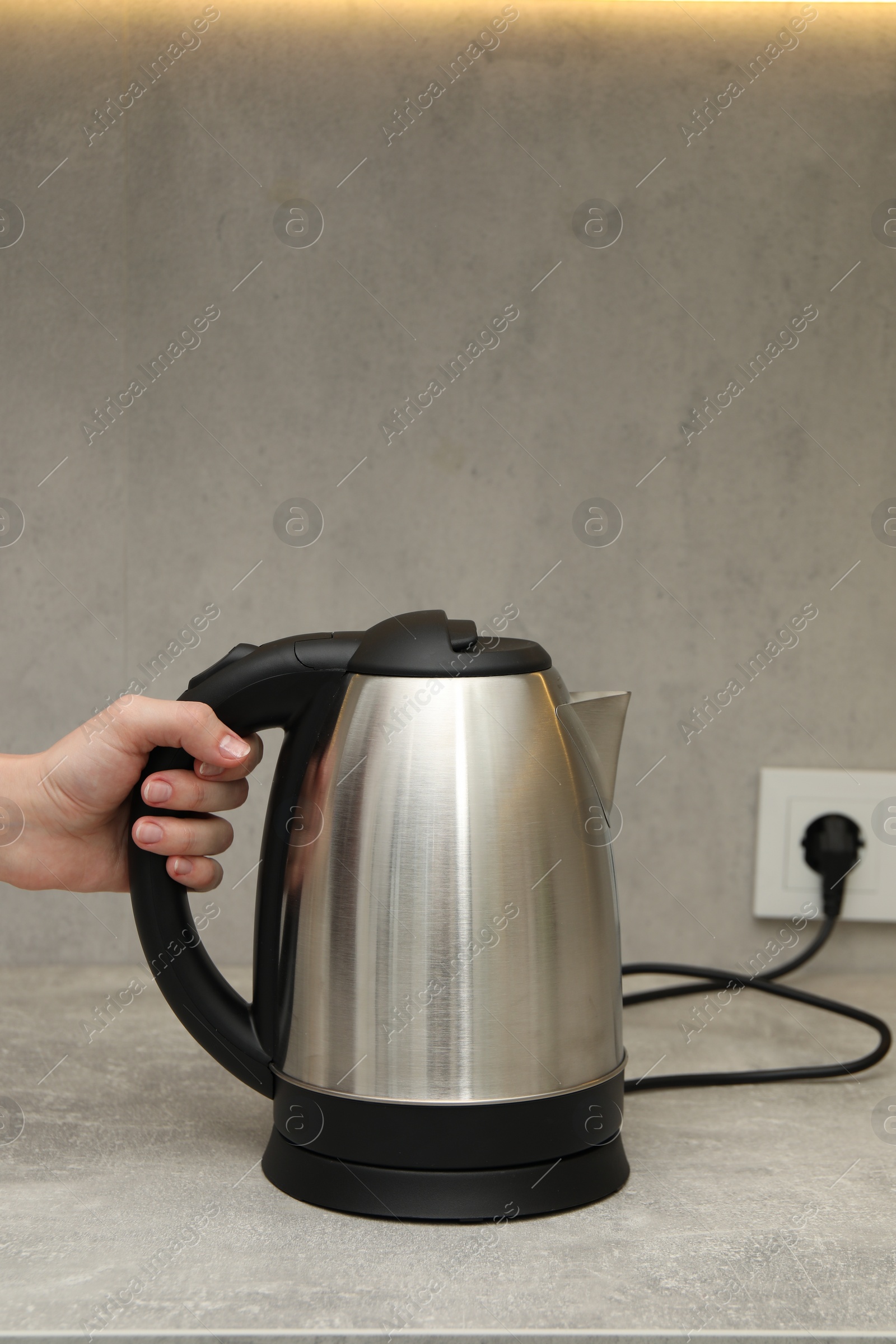 Photo of Woman with electric kettle in kitchen, closeup