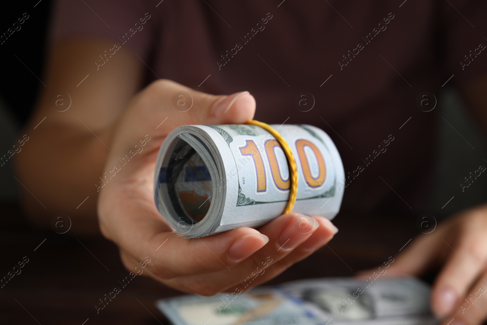 Photo of Woman holding rolled dollar banknotes, closeup view