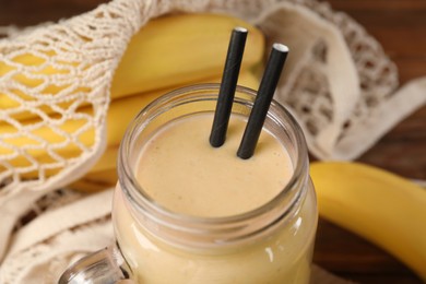 Photo of Mason jar with banana smoothie on wooden table, closeup