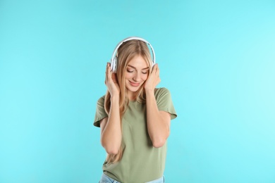 Photo of Beautiful young woman listening to music with headphones on color background